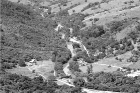 Fotografia de vale fluvial, vegetação e encostas.