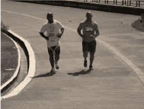 Dois corredores em pista, com sombras e curva visíveis.