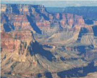 Fotografia do Grand Canyon, com paredes rochosas estratificadas e terreno profundamente recortado.